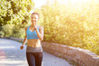 © skumer - Young smiling sporty woman running in park in the morning. Fitness girl jogging in park