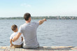 © Africa Studio - Father and son sitting on pier near river