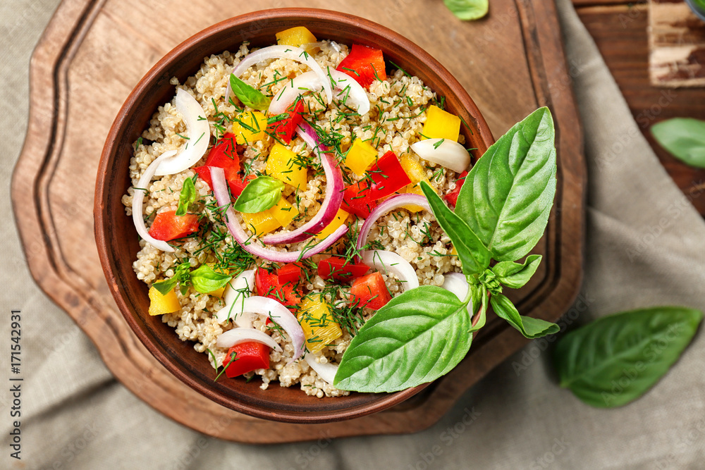 Salad with quinoa, tomatoes and basil leaves on table