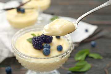 Poster - Teaspoon and dessert bowl with vanilla pudding on blurred background