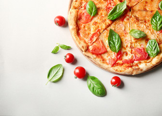 Wall Mural - Composition with pizza, cherry tomatoes and fresh basil on light background