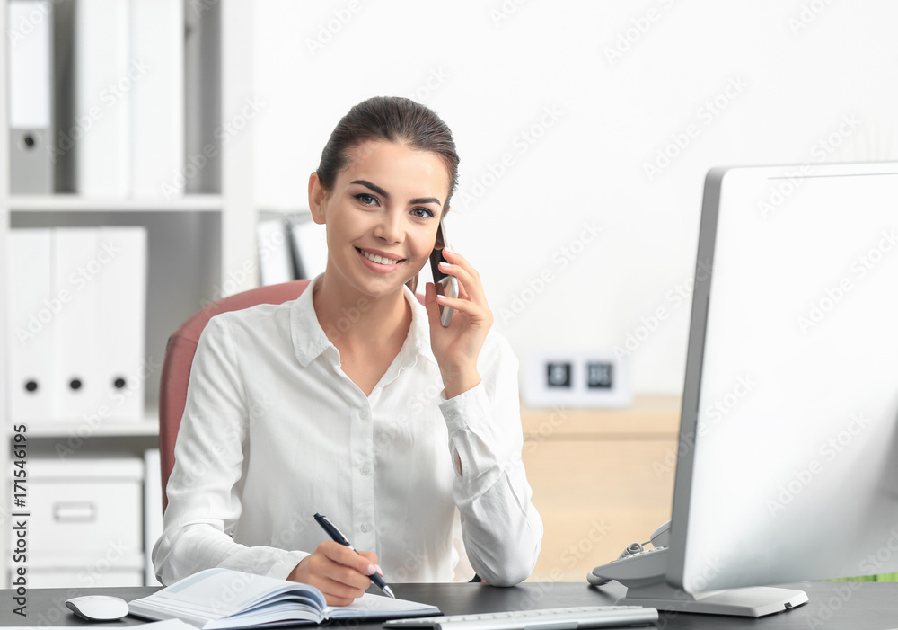 Young female receptionist talking on phone in office - obrazy, fototapety, plakaty 