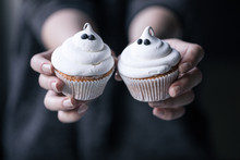 Female Hands Holding Two Halloween Cupcakes