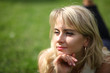 © Master Video - Beautiful young long-haired blonde posing for camera lying on grass. Young beautiful blond flirting with the camera. Blonde lying on green grass and looking at camera