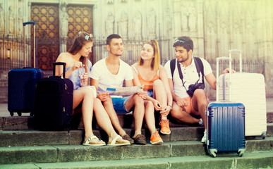 Group of young traveling people using paper map in city