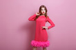 © artur - Cheerful beautiful young stylish woman in pink dress posing on pink background and looking at camera. Studio photo.