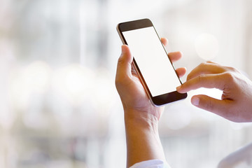 Man hands holding blank screen smartphone with blurred background.