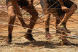 Mud race runners,racers overcome the obstacle from the ropes
