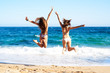 © Guille Faingold/Stocksy - Back view of girls in bikini jumping on beach