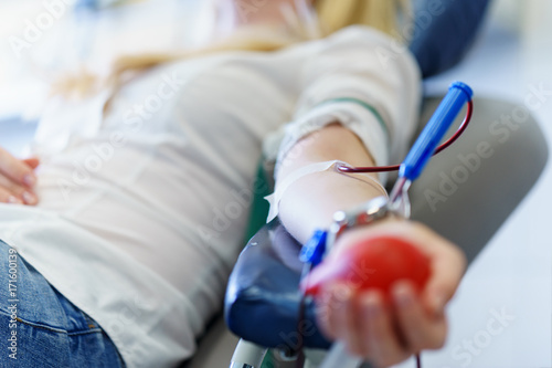 Fotomural young caucasian woman with toy heart in the hand donates blood for saving lives