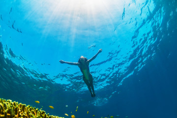 Happy family - girl dive underwater with tropical fishes in coral reef sea pool. Travel lifestyle, water sport outdoor adventure, swimming lessons on summer beach holiday with kids.