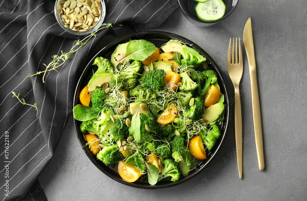 Superfood salad with broccoli and yellow tomato on grey background