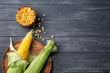 Fresh corn cobs and kernels on wooden background