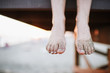 © Kristin Rogers Photography/Stocksy - Child's feet hanging off lifeguard stand with sandy feet