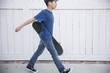 © Curtis Kim/Stocksy - Boy holding his skateboard and walking