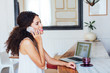 © BONNINSTUDIO/Stocksy - Side view of a businesswoman talking on phone working in a coffee bar.
