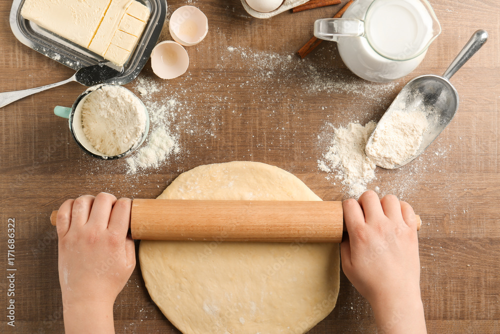 Woman rolling dough on kitchen table. Cooking classes concept