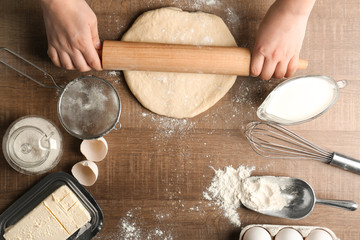 Woman rolling dough on kitchen table. Cooking classes concept