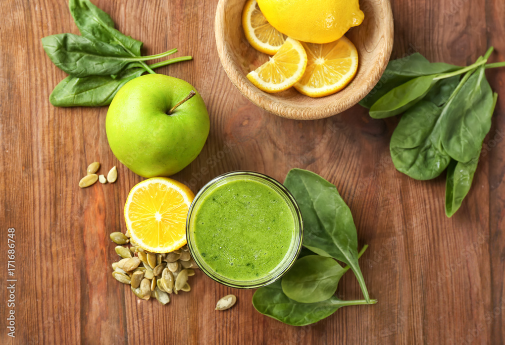 Glass of spinach smoothie on wooden background
