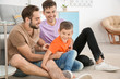 © Africa Studio - Homosexual male couple with foster son at home. Adoption concept