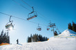 Silhouette of skier on snowy slope and low angle shot of a ski lift at ski resort in the mountains on a sunny winter day blue sky copyspace people riding top extreme activity sport recreation concept