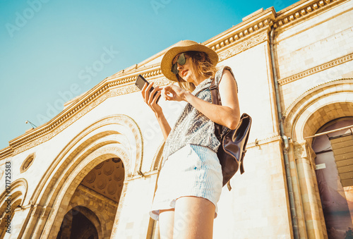 Fotografie, Tablou Young woman tourist in hat with backpack using gps navigation on phone