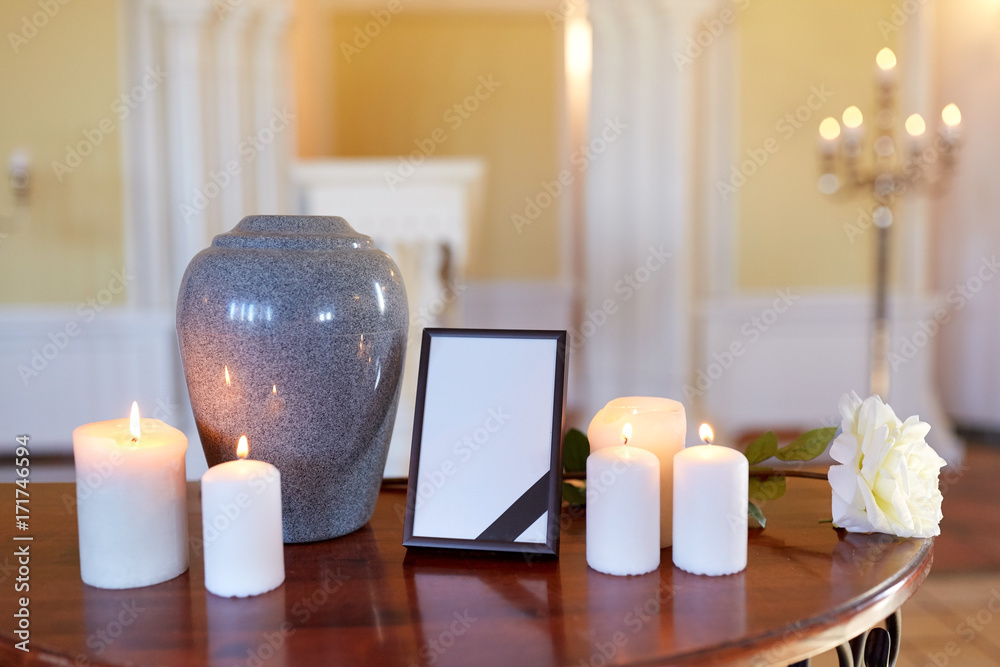 photo frame, cremation urn and candles in church - obrazy, fototapety, plakaty 