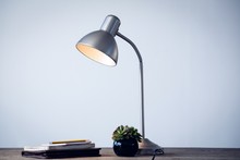 Illuminated Desk Lamp By Books On Table
