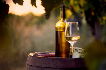 Glass of white wine and bottle with food at sunset