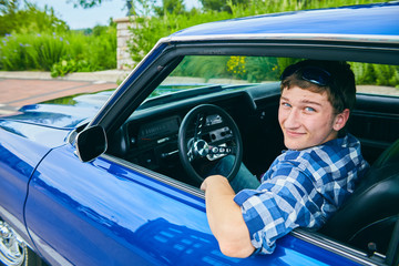 Portrait of happy young man driving blue car