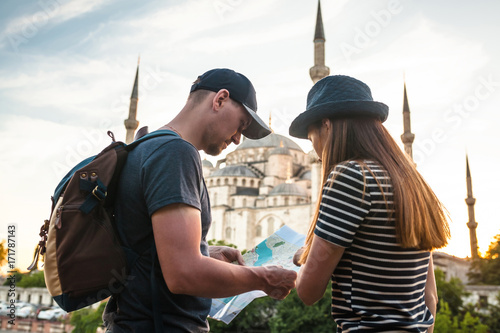 Foto A couple of tourists a young man and a pretty woman look at the map next to the world-famous Blue Mosque also called Sultanahmet in Istanbul, Turkey