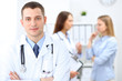 © rogerphoto - Friendly male doctor  on the background with patient  and physician
