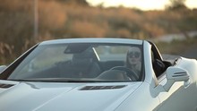 beautiful sexy girl with long hair in a leather jacket and leather pants in sunglasses sits in a cabriolet