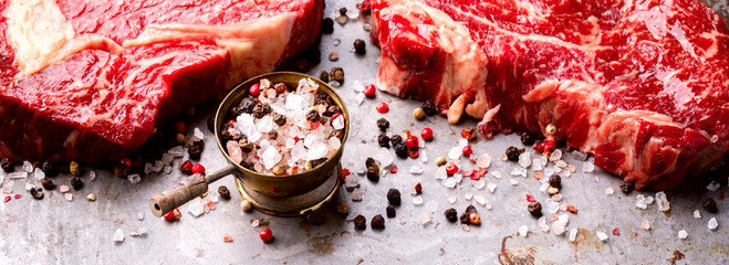 Wall Mural - Raw Fresh Marbled Meat Beef Steak. Seasonings on on the Gray Metal Background  Pepper and Salt Ingredients for Cooking