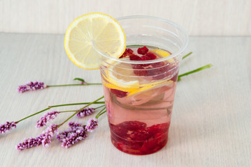 Still life: water with lemon and raspberries, wild flowers