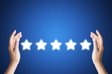 Hand holding five star symbol to increase rating of company with dark blue background, Copy space for text or headline