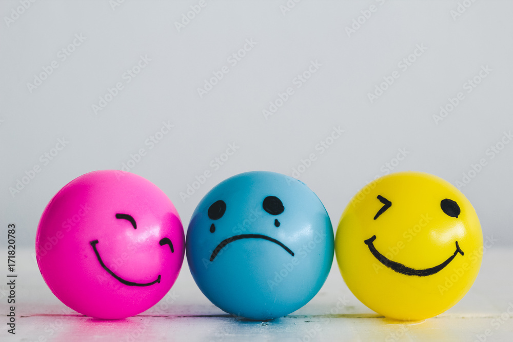Emotions balls: Happy smiley face pink and yellow ball and depress sadness ball crying in the middle, concept: Why are you so sad? - obrazy, fototapety, plakaty 
