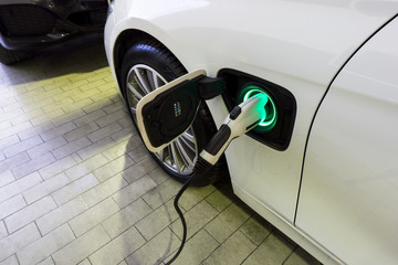 Power supply connect to electric car for add charge to the battery. Charging re technology industry transport which are the future of the Automobile.