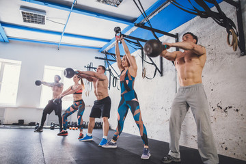 fitness and training concept - group of people with kettlebell exercising in gym