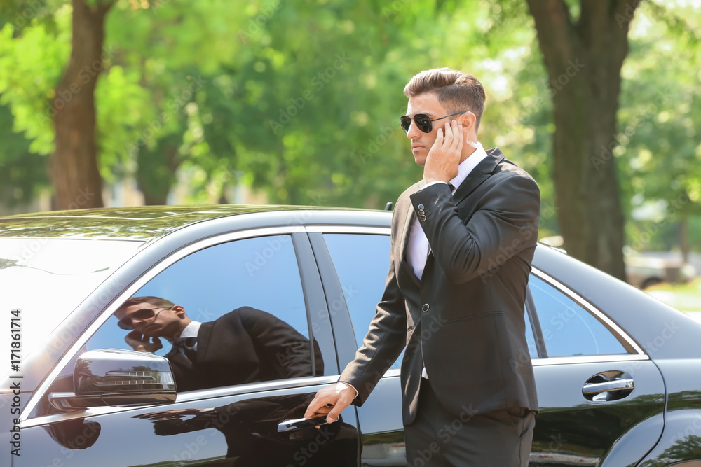 Handsome bodyguard near car outdoors