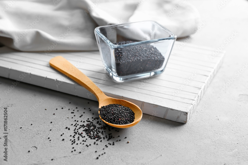 Black quinoa, glass bowl and wooden spoon on table