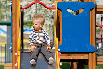 Wall Mural - One year old baby boy toddler at playground slide