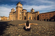 Girl sitting on a cobble-stone street to view Castello Estense of Renaissance town of Ferrara