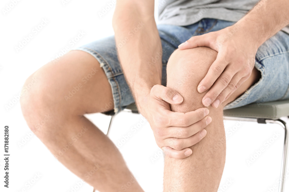 Young man suffering from leg pain on white background