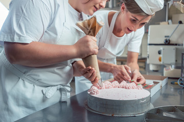 Konditor benutzt Spritzbeutel für Dekoration von Torte mit Buttercreme