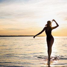 Silhouette Of Young Sexy Woman In Bikini Walking On The Beach