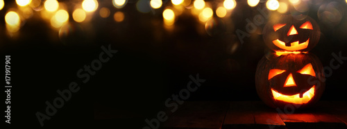 Cuadros en Lienzo Halloween Pumpkin on wooden table in front of spooky dark background
