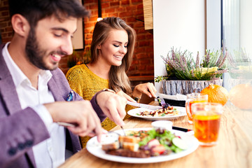 Happy young couple eating breakfast together in a cafe before heading to work in the morning