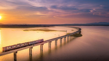 Aerial View The Train Is Running On The Bridge Over River Pa Sak Dam Lopburi Thailand And Beautiful Sunset