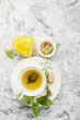 Ingredients for homemade lemon sauce vinaigrette dressing for salad with olive oil, salt, pepper, lemon, lemon zest, juice, garlic and herbs to taste. Top view on a light background.